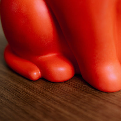 Close-up of a red ceramic cat urn with paws detail on a wooden surface. Features personalized cat urn for ashes, custom cat cremation urn, cat-shaped urn, sleeping cat statue urn, and pet urns for cats with engravable and personalized options.